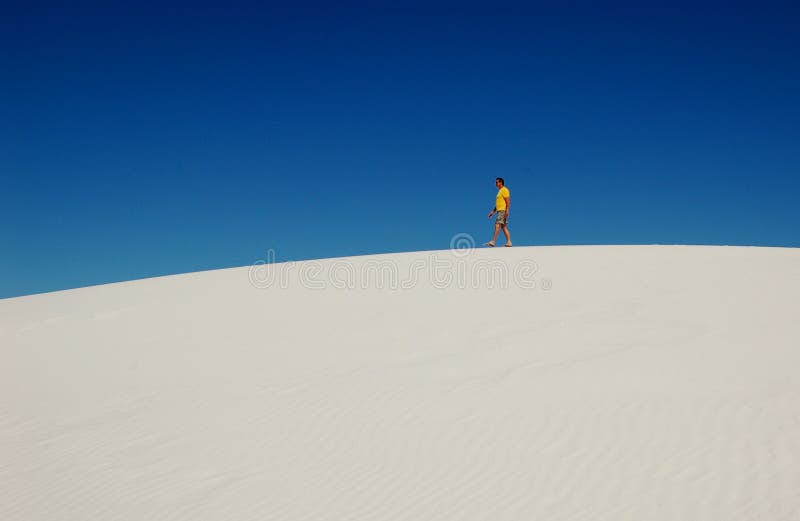 Hombre camina en contemplación través de de arena duna sobre el blanco playa, nuevo México.